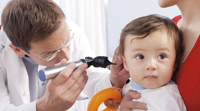Doctor examining ear with an otoscope